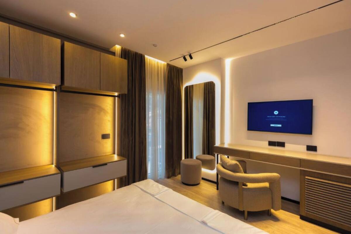 Una habitación de hotel moderna con cama, escritorio, televisor y zona de estar.