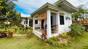Une maison à deux étages avec un porche couvert, un petit jardin et une clôture en bois.