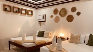 Une chambre d’hôtel avec deux lits, un climatiseur fixé au mur et des éléments décoratifs en forme d’œuvres d’art murales tissées.