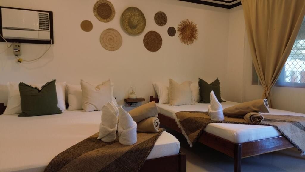 A hotel room with two beds, a wall-mounted air conditioner, and decorative wall art.