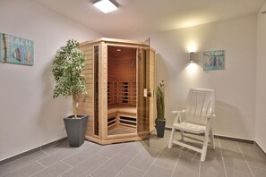 Ein Saunaraum mit einer Holzbänken, einem Stuhl und zwei Blumentöpfen.