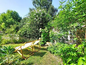A garden with a wooden swing, dense foliage, and a stone wall. - La Dolce Vita Brezhoneg by Interhome (Tréméven)