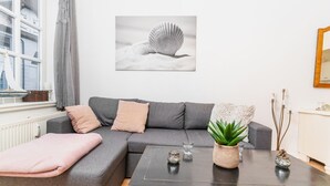 A modern living room with a grey sofa, a coffee table, and a potted plant. - fewo1846 - Koje Sansibar - fewo1846 - Koje Sansibar / centrally located (Flensburg)
