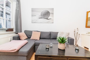 A modern living room with a grey sofa, a coffee table, and a potted plant. - fewo1846 - Koje Sansibar - fewo1846 - Koje Sansibar / centrally located (Flensburg)