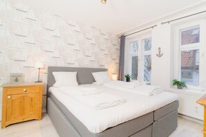 A bedroom with a bed, bedside tables, a window, and a wall with a nautical pattern. - fewo1846 - Admirals Koje - fewo1846 - Admirals Koje / centrally located (Flensburg)