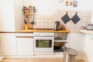 A kitchen with a stove, oven, and various utensils on the counter. - fewo1846 - Piratenkoje - fewo1846 - Piratenkoje / centrally located apartment in an old building (Flensburg)