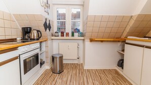 Eine kleine Küche mit Herd, Backofen und einem Fenster über der Spüle.