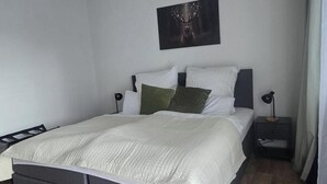 Une chambre à coucher avec un lit, une table de chevet, une lampe et un tableau accroché au mur.