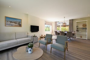 A modern living room with a sofa, armchairs, a coffee table, and a TV. There's a dining area with a table and chairs, and a bookshelf. - Enjoy comfort, tranquility and waterside living at Zilt&Zalig on Oranjeplaat. Modern holiday home with private jetty near Lake Veere in Zeeland (Arnemuiden)