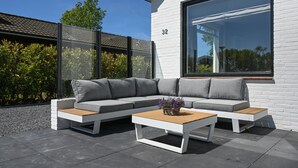 A modern outdoor seating area with a sectional sofa and a coffee table, adjacent to a white brick building with large windows. - Holiday home close to the water, with a private berth at the jetty, quiet location (Arnemuiden)