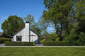 A white building with a chimney, surrounded by greenery and trees. - Enjoy comfort, tranquility and waterside living at Zilt&Zalig on Oranjeplaat. Modern holiday home with private jetty near Lake Veere in Zeeland (Arnemuiden)