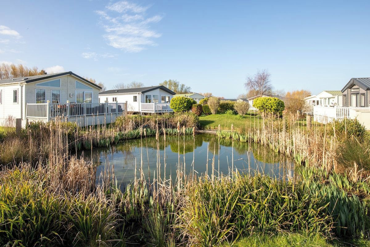 A row of mobile homes with a pond in the foreground.