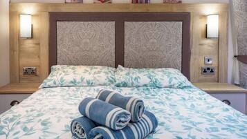 A hotel room with a bed, two bedside lamps, and a headboard with a patterned design.
