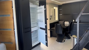 Eine moderne Küche mit Einbaukühlschrank, eine Essecke mit Tisch und Stühlen sowie eine Treppe, die zu einer anderen Ebene führt.