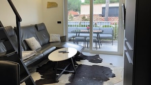 Ein modernes Wohnzimmer mit einem schwarzen Ledersofa, einem runden Couchtisch und einem Kuhfellteppich.