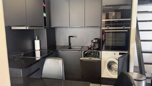 Eine kompakte Küche mit integrierter Waschmaschine, einer Kaffeemaschine und einer Mikrowelle.
