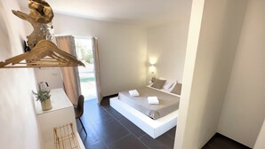 A modern bedroom with a large bed, a wooden hanger, a small plant, and a view of the outdoors. - Oasis of peace and serenity, nestled in the countryside. (Mesagne)