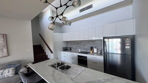 Una cocina moderna con encimera de mármol, electrodomésticos de acero inoxidable y un candelabro original.