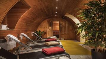 Ein Spa-Raum mit Holzausbau, einer Sauna, Handtüchern und einer Topfpflanze.