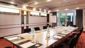 A conference room with a long table, chairs, and a large window with curtains. - Offenburg City by Belvilla- Standard Twin Room (Offenburg)