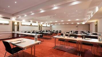 A conference room with multiple tables, chairs, and a carpeted floor.
