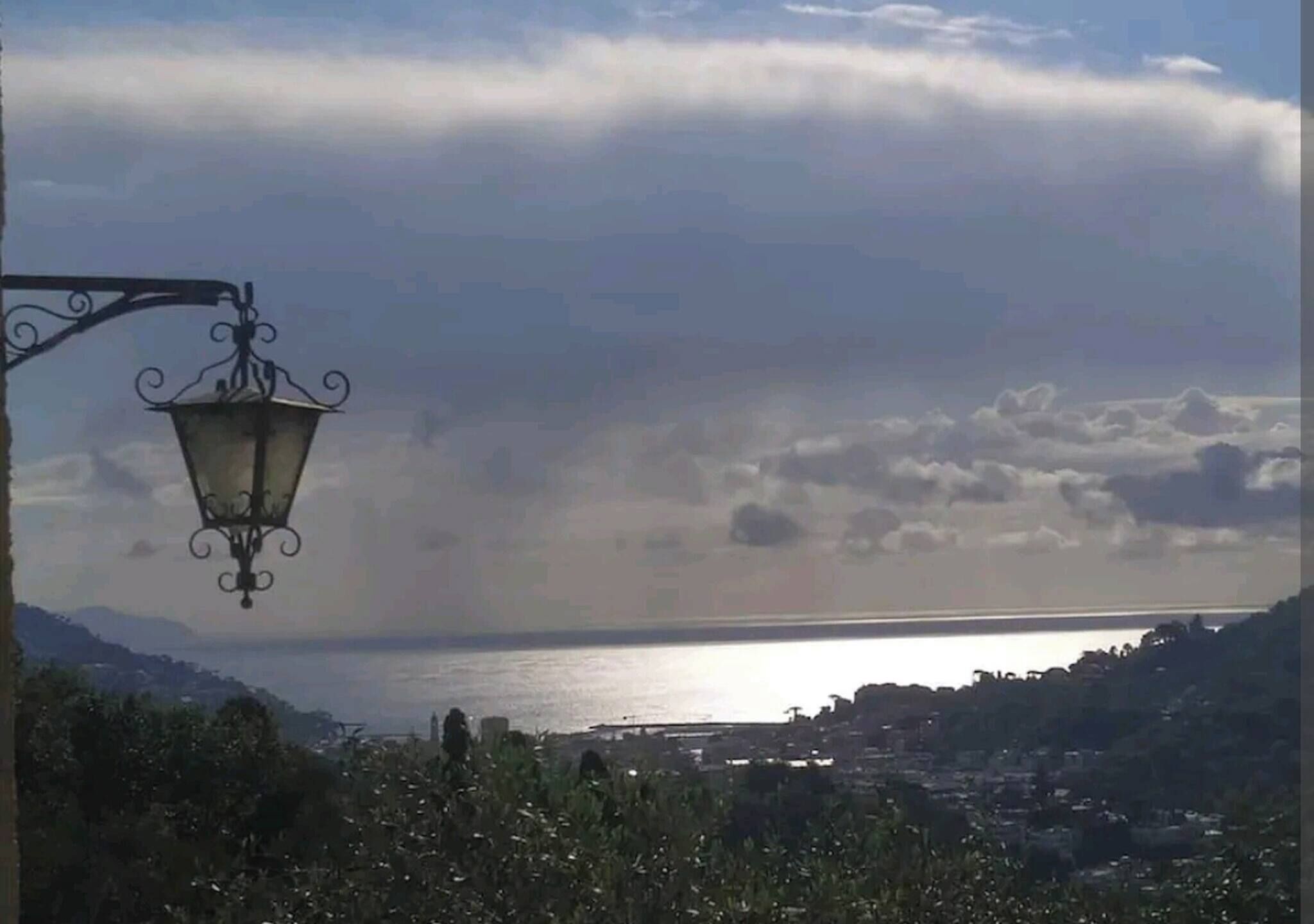 A coastal view with a street lamp, a body of water, and a distant cityscape.