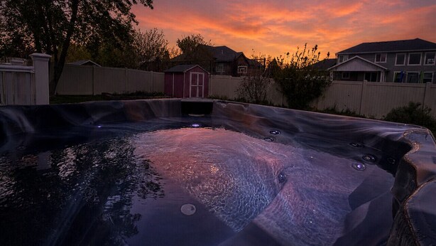 Ein Whirlpool in einem Garten mit Abendhimmel.