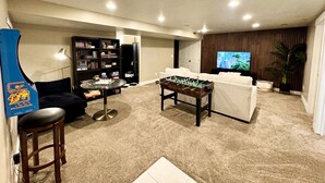 Ein Wohnzimmer mit Tischfußball, einer Couch, einem Bücherregal und einem Fernseher.