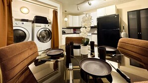 Eine kleine Küche mit Esstisch, Stühlen, Kühlschrank und Waschmaschine.