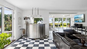 Una cuina moderna amb una illa gran, zona de menjador amb vistes i saló amb sofà de cuir.
