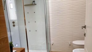 Un baño moderno con ducha de vidrio, un lavamanos blanco y un inodoro.
