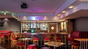 Un espace bar agrémenté d’un néon, de sièges rouges et d’un comptoir.