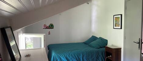 Un dormitorio con cama, cómoda de madera, lámpara colgante y una puerta.