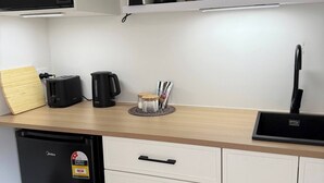Una cocina moderna con microondas, cafetera, hervidor y pileta.