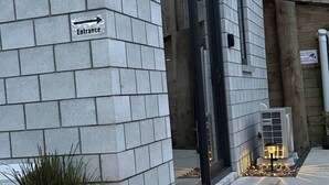 Entrada de edificio con un cartel que indica la dirección, una puerta y un pequeño accesorio de iluminación exterior.