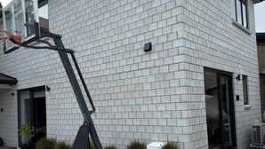 Un edificio moderno con fachada de ladrillo, aro de baloncesto y un pequeño jardín.
