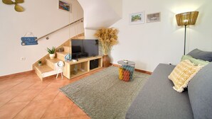 Een woonkamer met een televisie, bank en een trap.
