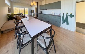A modern kitchen with a central island, a dining area with a long table and chairs, and a view of the outdoors through large windows. - Awesome home in Sydals with WiFi (Sydals)