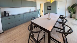 Una cucina moderna con mobili color petrolio, un tavolo da pranzo in legno e sedie nere.
