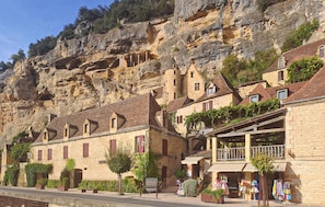Un bâtiment en pierre doté d’un balcon, d’une enseigne et d’un escalier menant à une falaise.