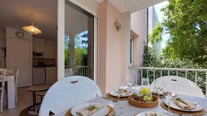 A dining area with a table set for four, including plates, cutlery, and glasses. - Appartement proche plage (Saint-Palais-sur-Mer)