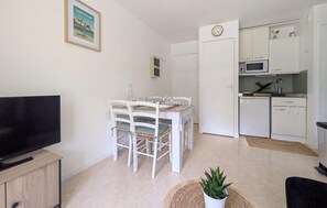 Un espace de vie compact comprenant un coin repas, une kitchenette et un téléviseur posé sur un meuble en bois.