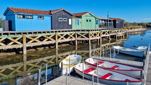 A waterfront property with colorful wooden buildings, a dock, and moored boats. - Appartement proche plage (Saint-Palais-sur-Mer)