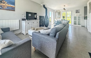 A modern living room with a sofa, TV, and a fireplace. - Charmante maison proche plage (Le Vivier-sur-Mer)