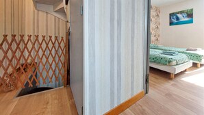A room with a wooden staircase, a bed with green bedding, and a painting of a waterfall on the wall. - Awesome home in Sauzé-entre-Bois with WiFi (Sauzé-entre-Bois)
