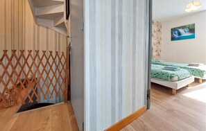 Ein Zimmer mit einer Holztreppe, einem Bett mit türkisgrüner Bettwäsche und einem Wandbild eines Wasserfalls.
