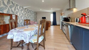 A dining area with a table set for two, a wooden cabinet, and a kitchen with a microwave, oven, and red kettle. - Awesome home in Sauzé-entre-Bois with WiFi (Sauzé-entre-Bois)