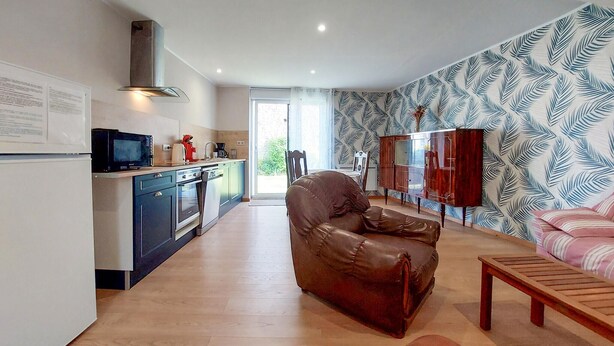 A modern kitchen with a microwave, oven, and sink, a leather sofa, a wooden bench, and a patterned wallpaper. - Awesome home in Sauzé-entre-Bois with WiFi (Sauzé-entre-Bois)