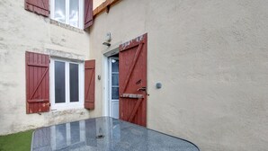 A narrow outdoor corridor with a glass table, red shutters, and a beige wall. - Awesome home in Sauzé-entre-Bois with WiFi (Sauzé-entre-Bois)