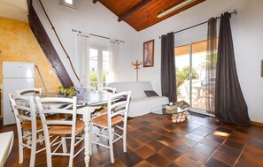 A room with a dining table, chairs, a sofa, a bed, and a view of the outdoors. - Villa pro. mer grande piscine (Ghisonaccia)